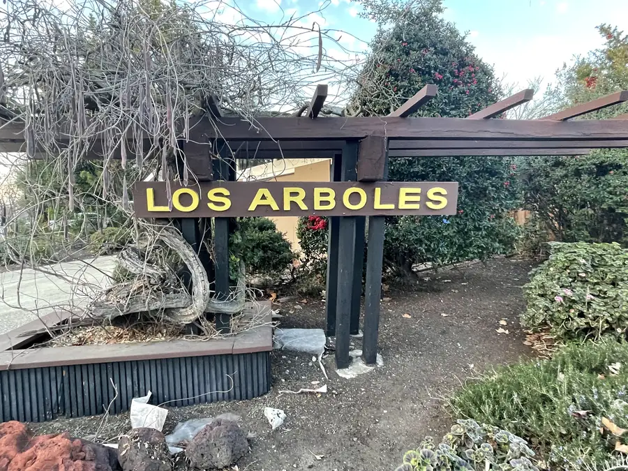 The Los Arboles tract entry sign: yellow lettering on a dark post-and-beam frame.